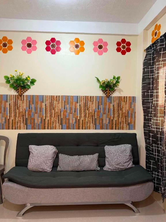a green couch in a room with flowers on the wall at DC Travellers Inn Unit E 3rd Fl in Malolos