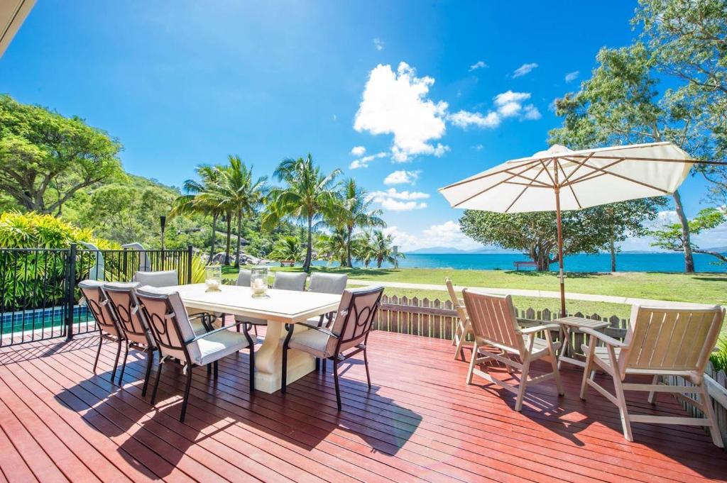 a deck with a table and chairs and an umbrella at Eeast on Picnic in Picnic Bay