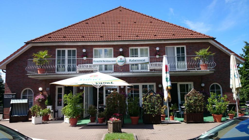 ein Gebäude mit einem Regenschirm und Pflanzen davor in der Unterkunft Hotel und Restaurant Rabennest am Schweriner See in Raben Steinfeld
