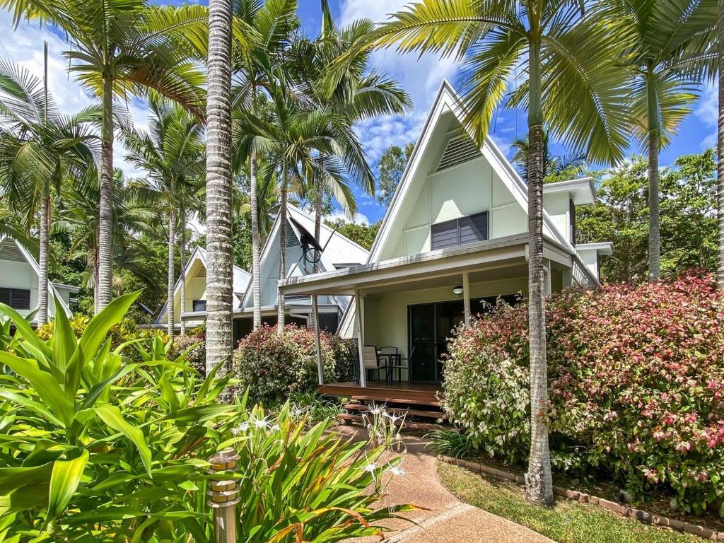a house with palm trees in front of it at Canopy Chalet 10 in Nelly Bay