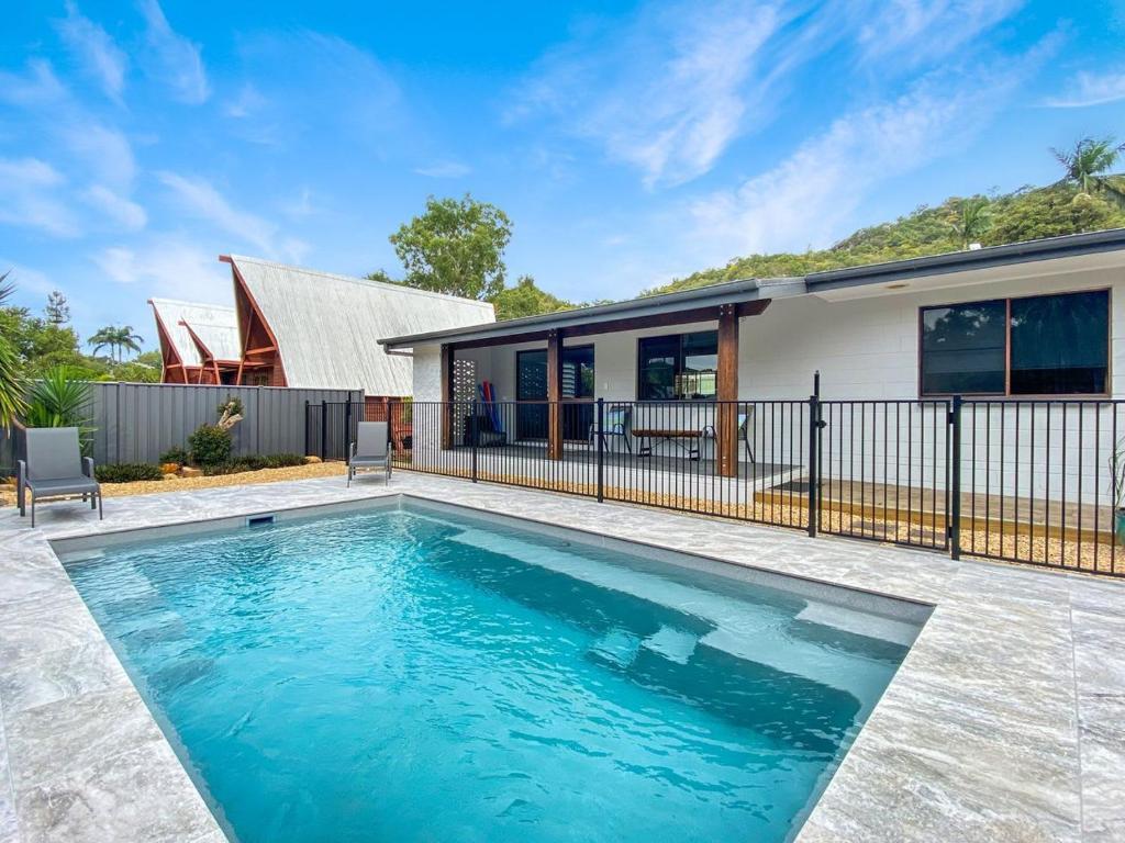 a swimming pool in front of a house at Nerita Nook in Nelly Bay