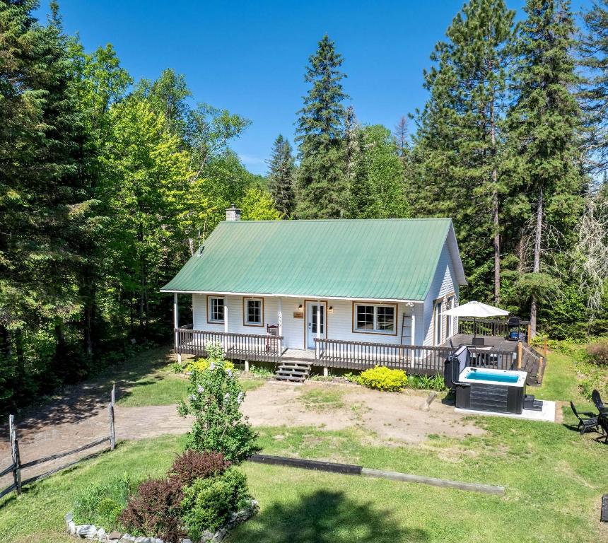 a small white house with a green roof at Pool Table et Nature - Chalet de la riviere in Saint-Alexis-des-Monts