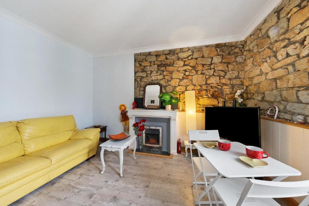 a living room with a yellow couch and a stone wall at Appartement centre de Crozon in Crozon