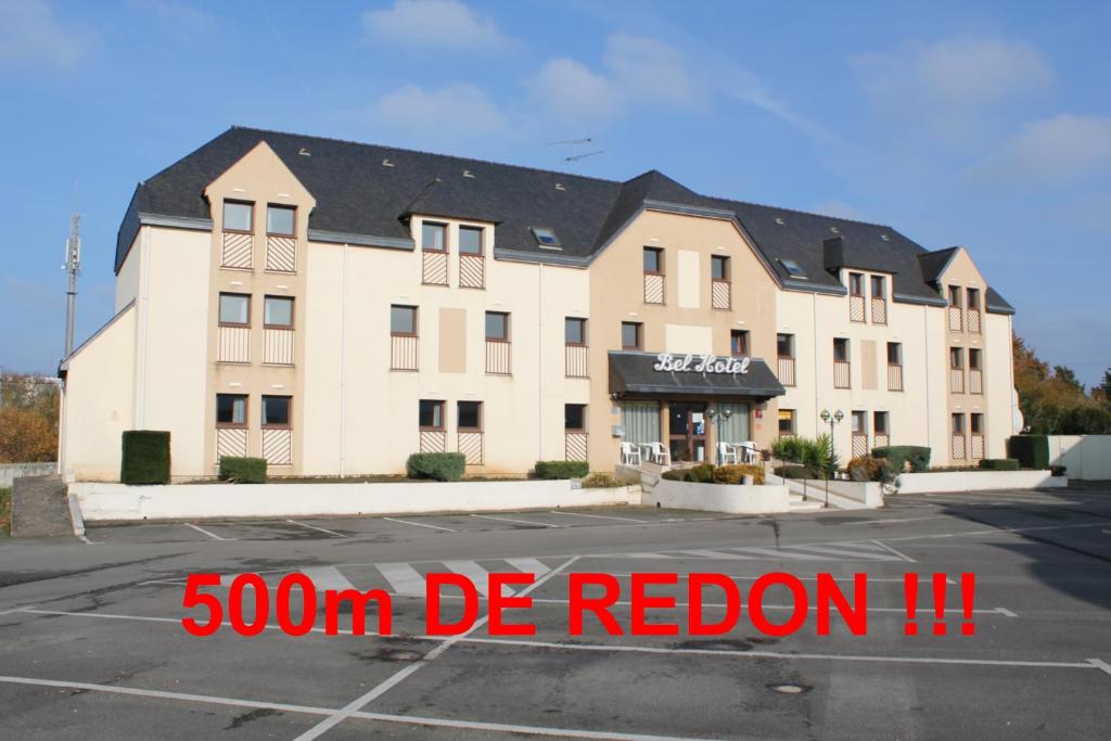 un bâtiment avec un panneau rouge en face d'un parking dans l'établissement Bel Hotel, à Saint-Nicolas-de-Redon