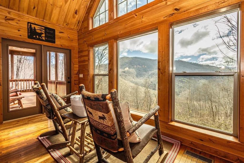 a dining room with two rocking chairs and windows at Millstone Lodge Cabin in Bryson City