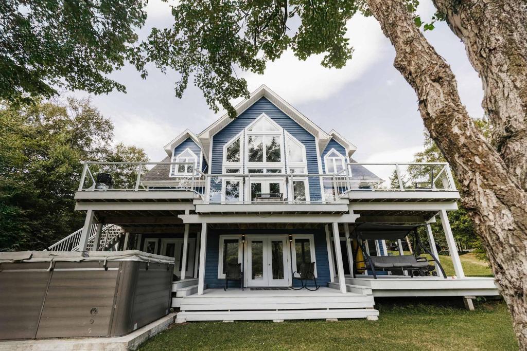 a blue house with a tree at Luxurious Lakeside Chalet with Swim Spa in South Brook