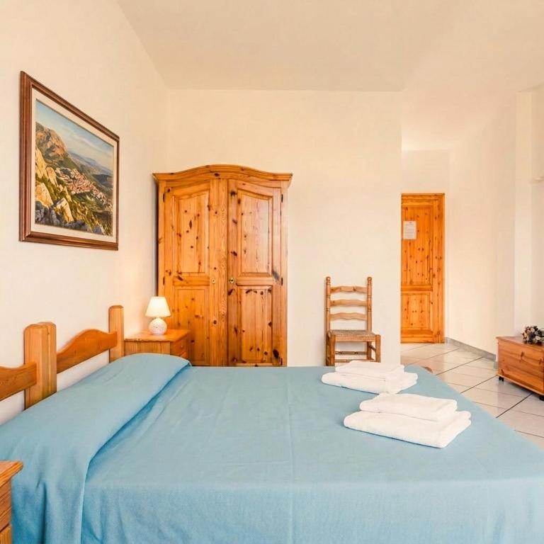 a bedroom with a blue bed with two towels on it at Borgo Moderno in Irgoli