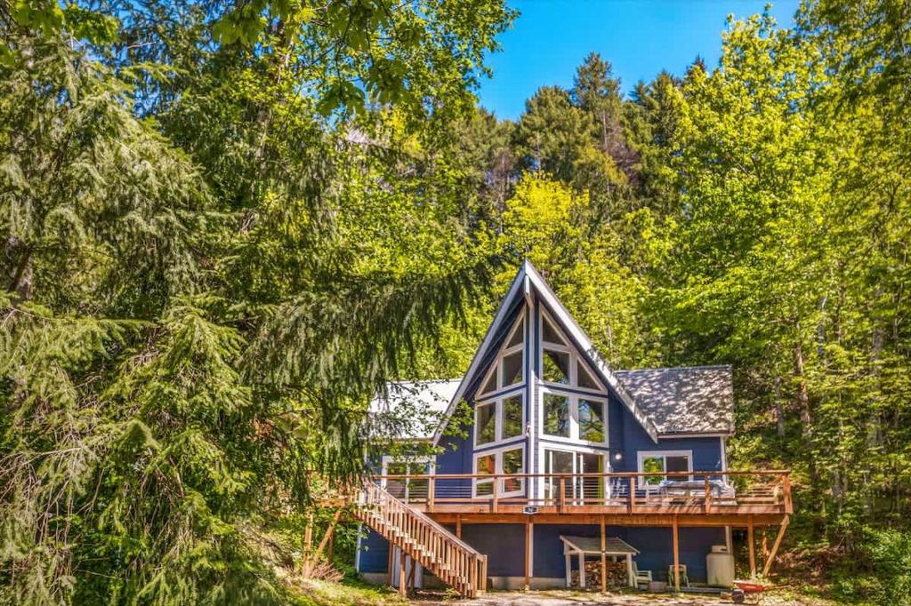 a blue house with a deck in the woods at A-Frame Cabin Dock Access & Views BBQ in Hoodsport