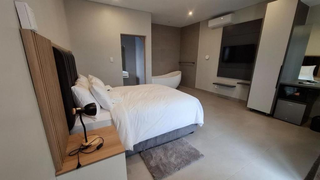 a bedroom with a white bed and a bathroom at Lehumo Guesthouse in Mogales
