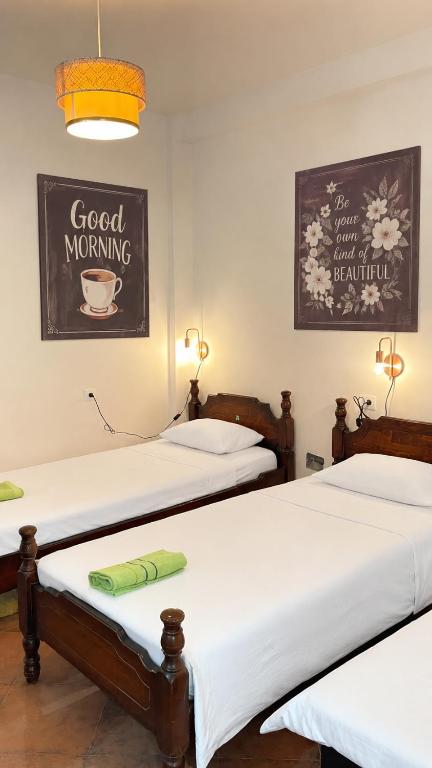 two beds in a room with a good morning sign on the wall at Hostel Backpacker in Ulcinj