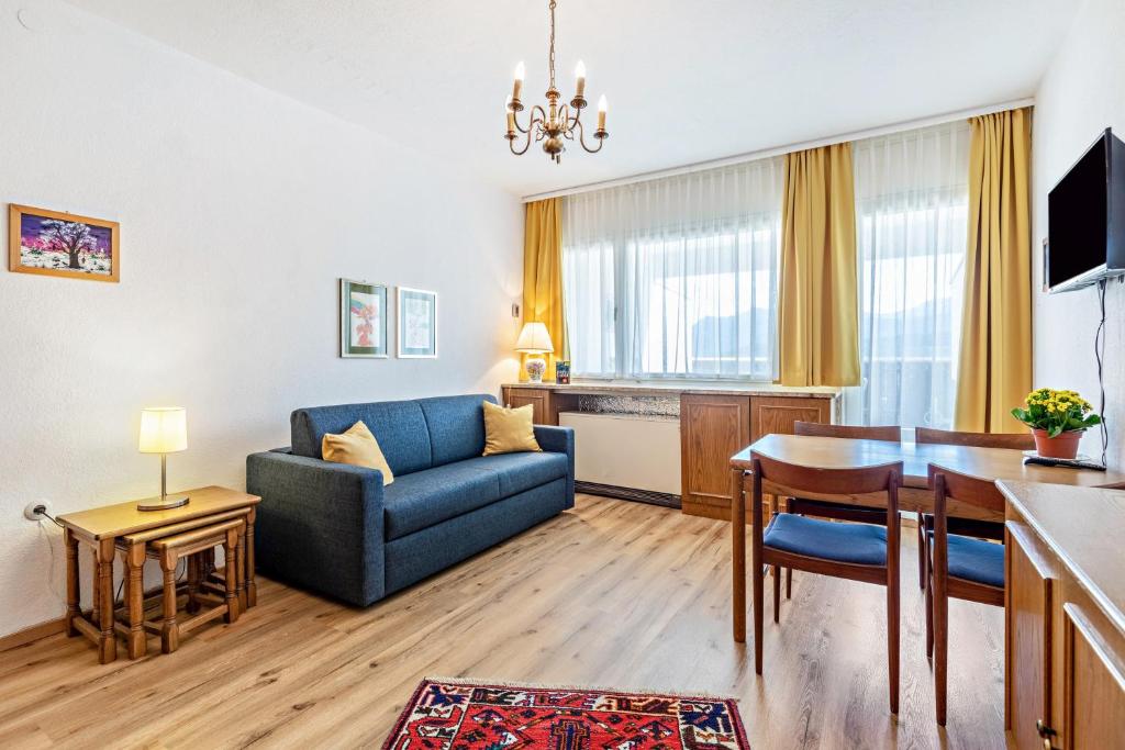 a living room with a blue couch and a table at Grimmingblick Apartment mit Pool in Reith