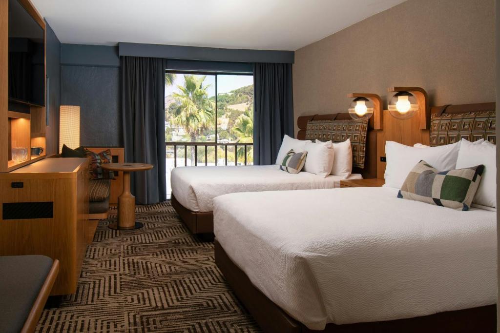 a hotel room with two beds and a balcony at Marin Hilltop Hotel in San Rafael