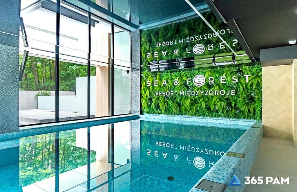 a swimming pool with a sign on the side of a building at 365PAM - Apartament Sea & Forest - BASEN KRYTY I ZEWNĘTRZNY, JACUZZI, SAUNA, GARAŻ W CENIE in Międzyzdroje