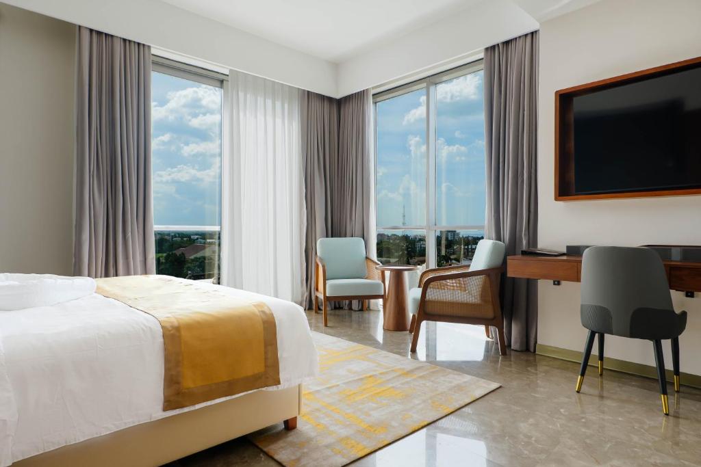 a hotel room with a bed and a desk and windows at Abantu Hotel in Dar es Salaam