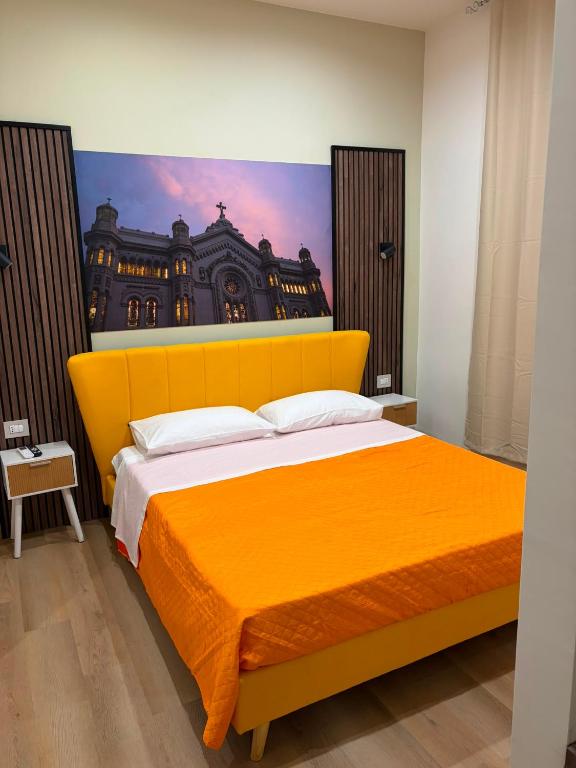 a bedroom with a yellow bed with a painting on the wall at Domus Rhegium in Reggio di Calabria
