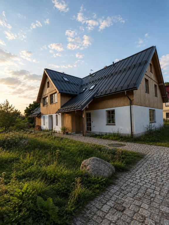 a barn with a metal roof on a field at Apartmány Vysoké in Vysoké nad Jizerou