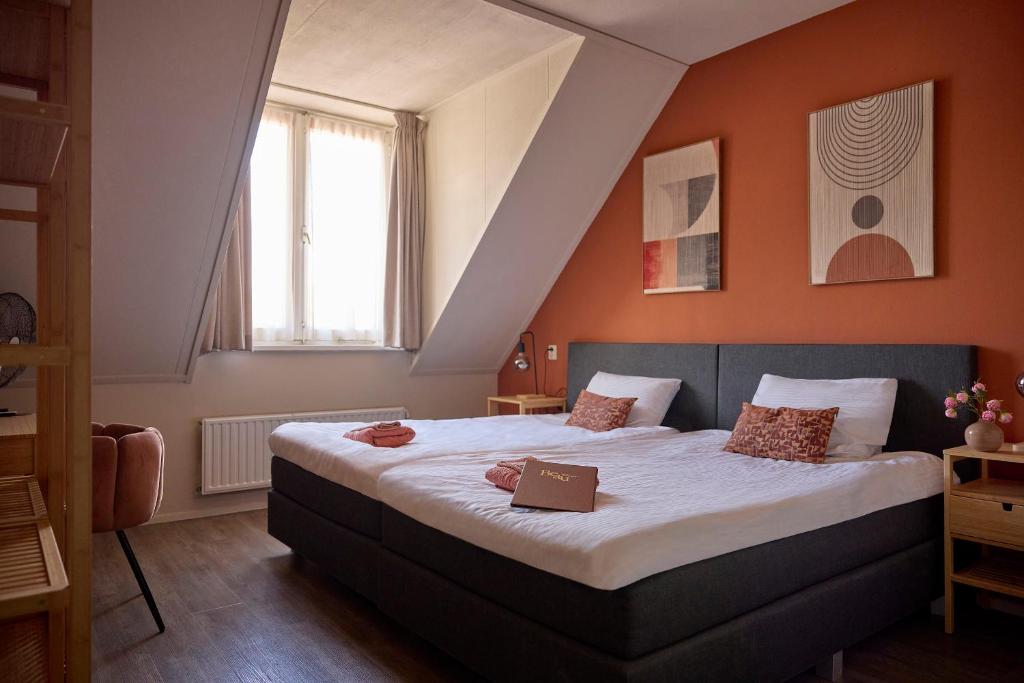 a bedroom with a large bed with orange walls at Hotel BEAU in Bergeijk