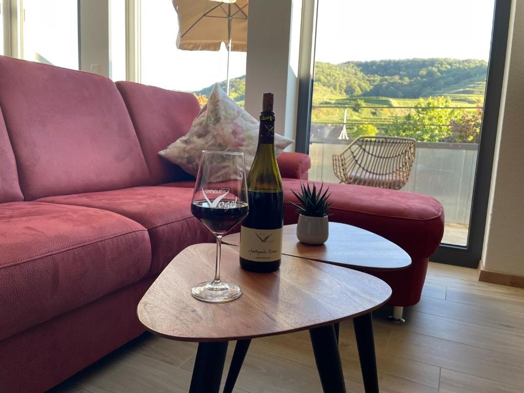 a bottle of wine on a table next to a couch at Apartment Steinkauz in Vogtsburg