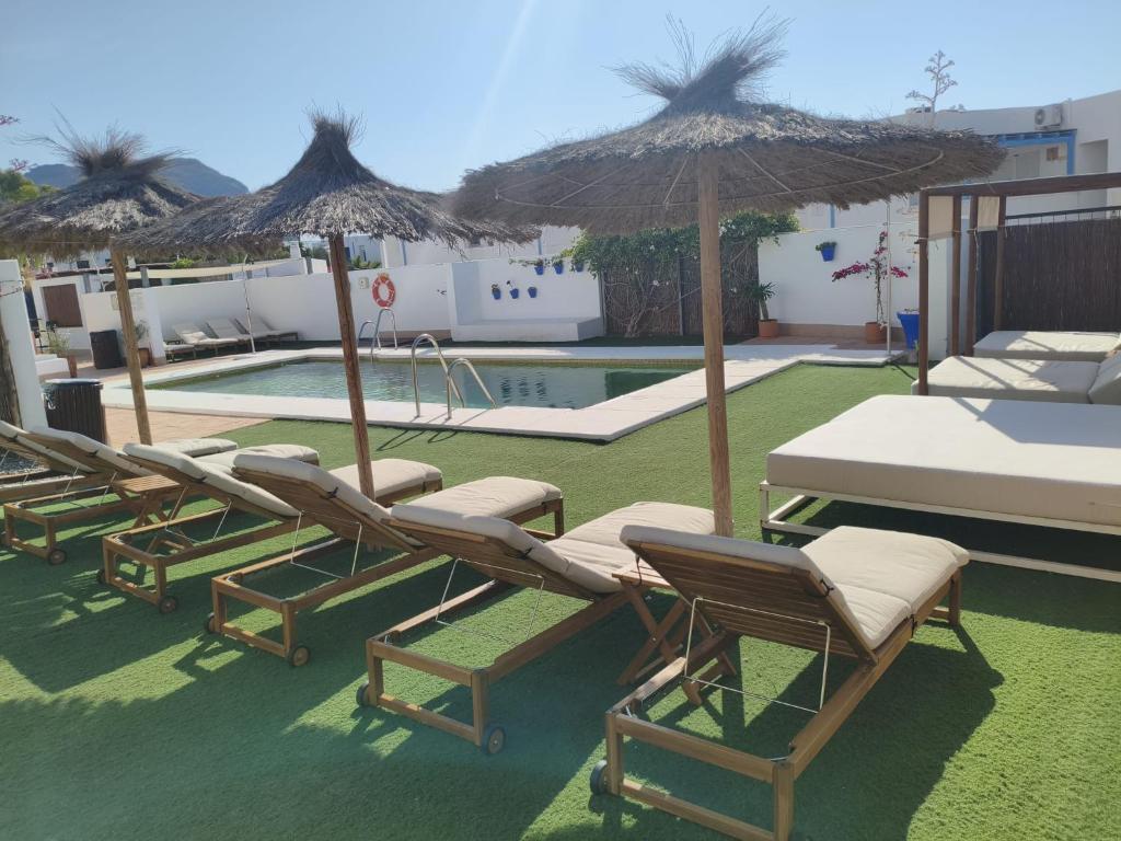 a group of lounge chairs and umbrellas next to a pool at Calachica Las Negras Hotel Boutique in Las Negras