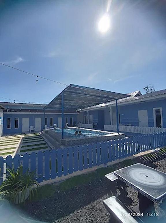 a blue fence in front of a building with a pool at Hotel O D Longan Cottage in Kampung Tikam Batu