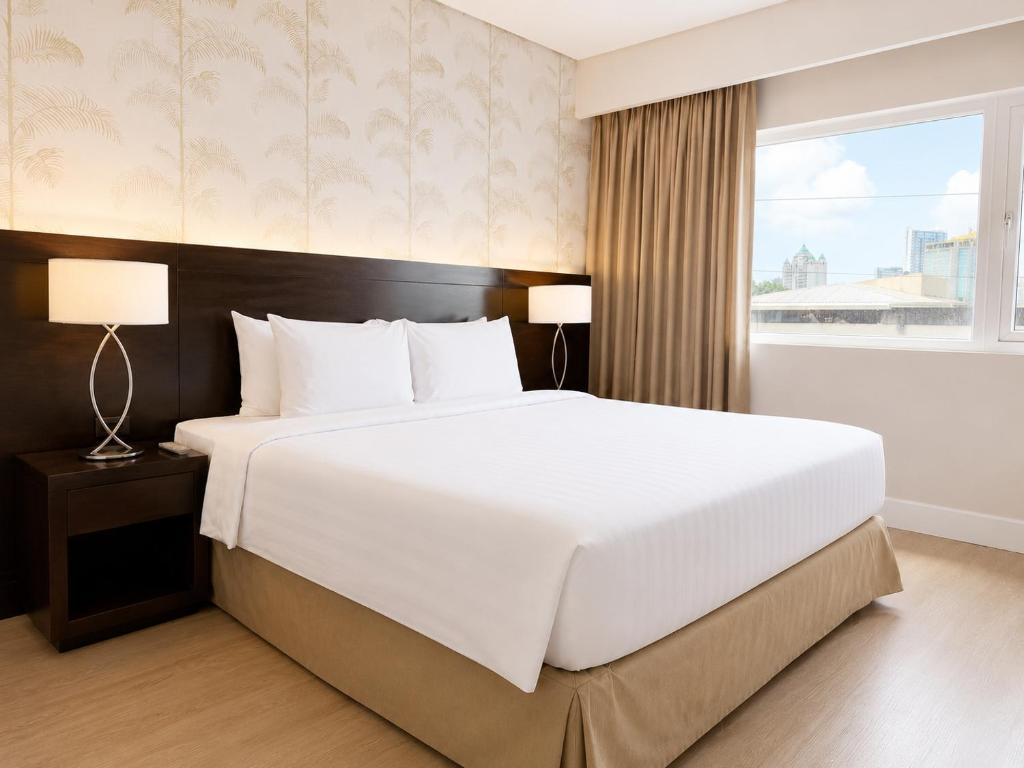 a large white bed in a room with a window at Harolds Hotel Cebu in Cebu City