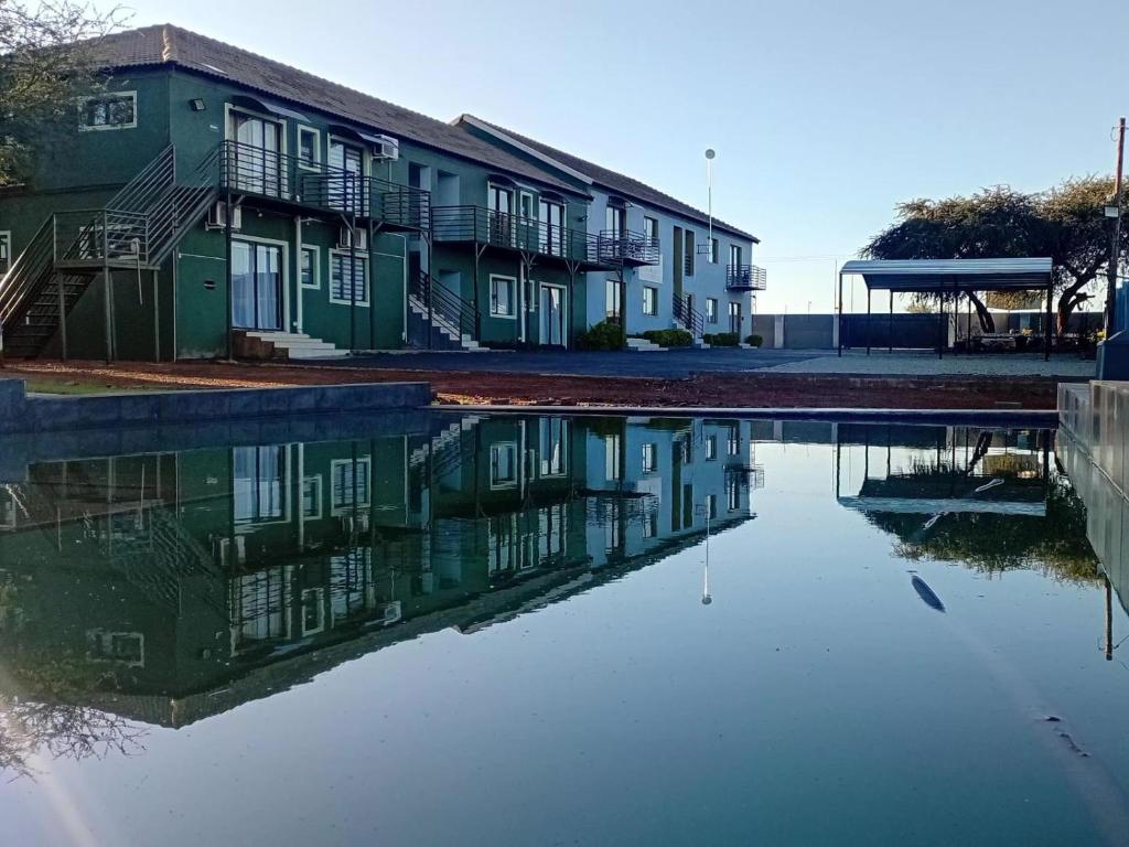 a building with its reflection in a body of water at Eden Villas Guesthouse in Kuruman