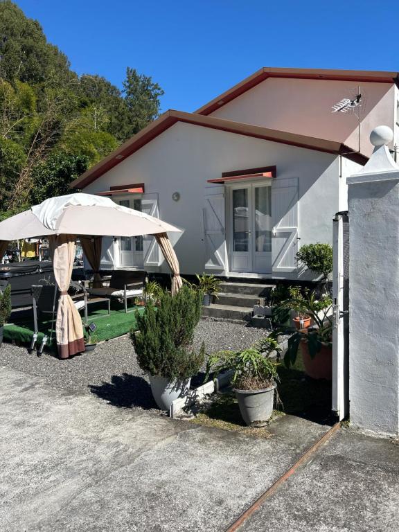 a house with an umbrella and some plants at Chez Ava in Salazie