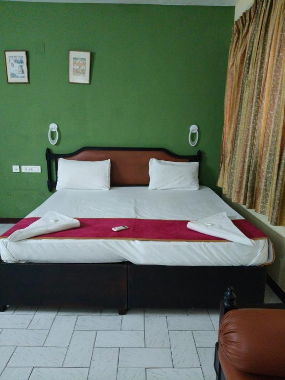 a bedroom with a large bed with a green wall at Bluemoon Hotel in Cochin