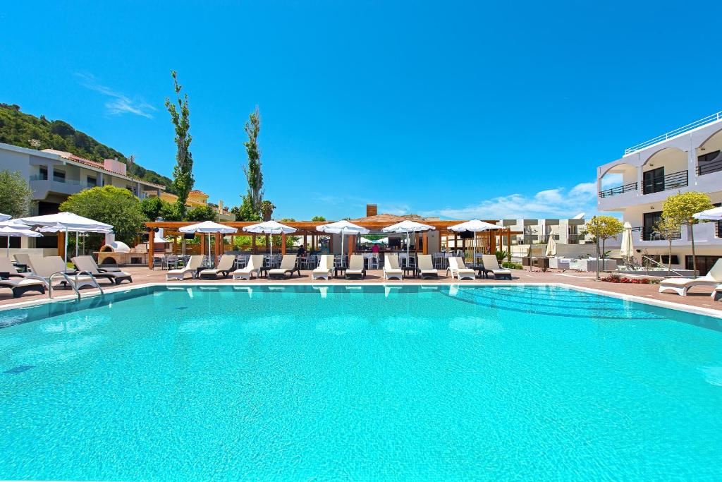 a large swimming pool with chairs and umbrellas at Sunny Days Hotel in Ixia