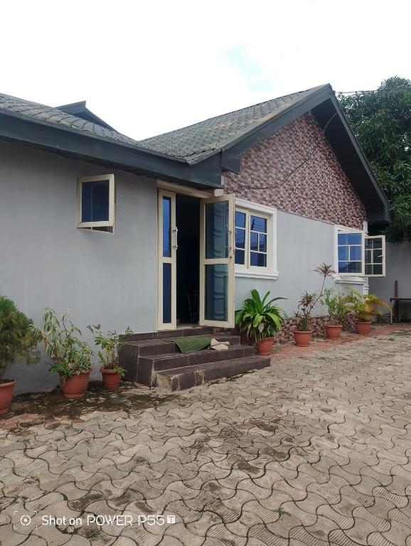 a white house with potted plants in front of it at Extramile Hotel and Lounge in Ibadan