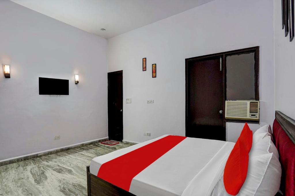 a bedroom with a large white bed with red pillows at Hotel O Rest & Zone Hotel in Greater Noida