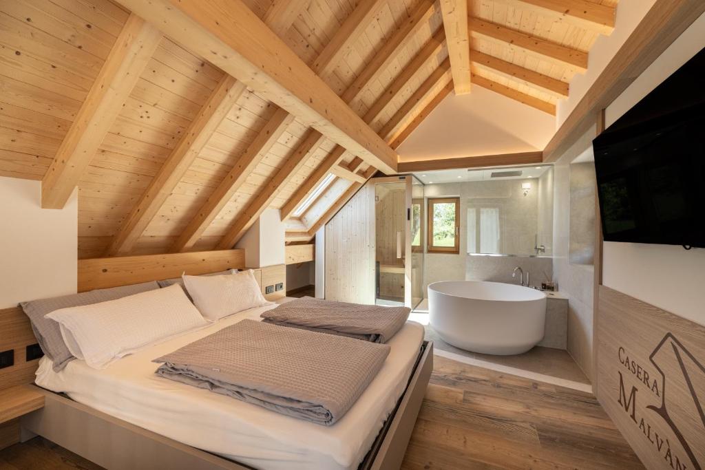 a bedroom with a large bed and a bath tub at Casera Malvan, private wellness chalet in Belluno