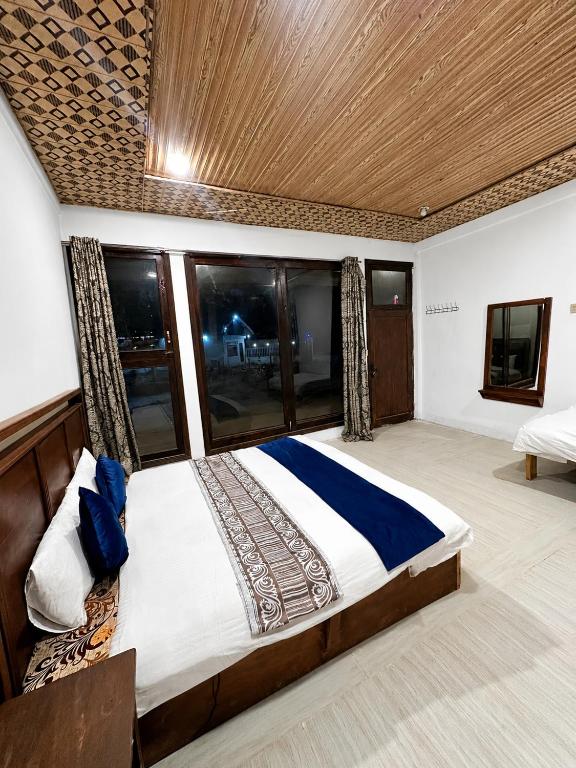 a bedroom with a large bed with windows at Blue Bird Resort Utror Swat in Utrot