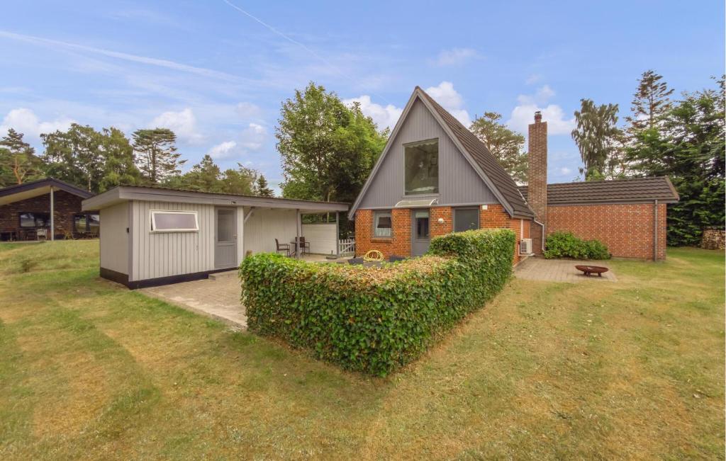 a house with a hedge in front of a yard at Beautiful Home In Ørsted With Wifi in Ørsted