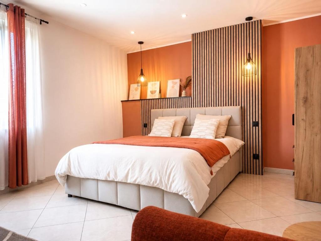 a bedroom with a large bed with orange walls at Studio Cosy tout équipé 40m2 - Entrée autonome - Parking gratuit in Distroff