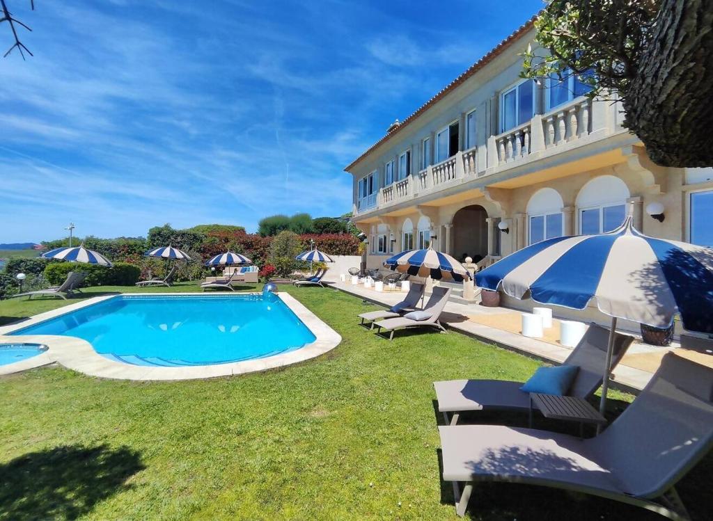 a villa with a swimming pool with lawn chairs and umbrellas at Suite con Vista a las Islas Cies in Vigo
