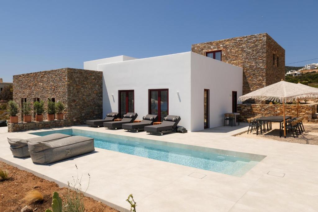 a villa with a pool in front of a house at Proper Stone Villa - Antiparos in Agios Georgios
