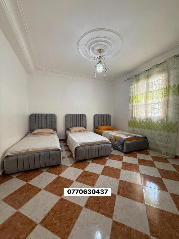 a bedroom with two beds and a checkered floor at حي السلام سيدالمجدوب in Sidi Mohammed Medjoub