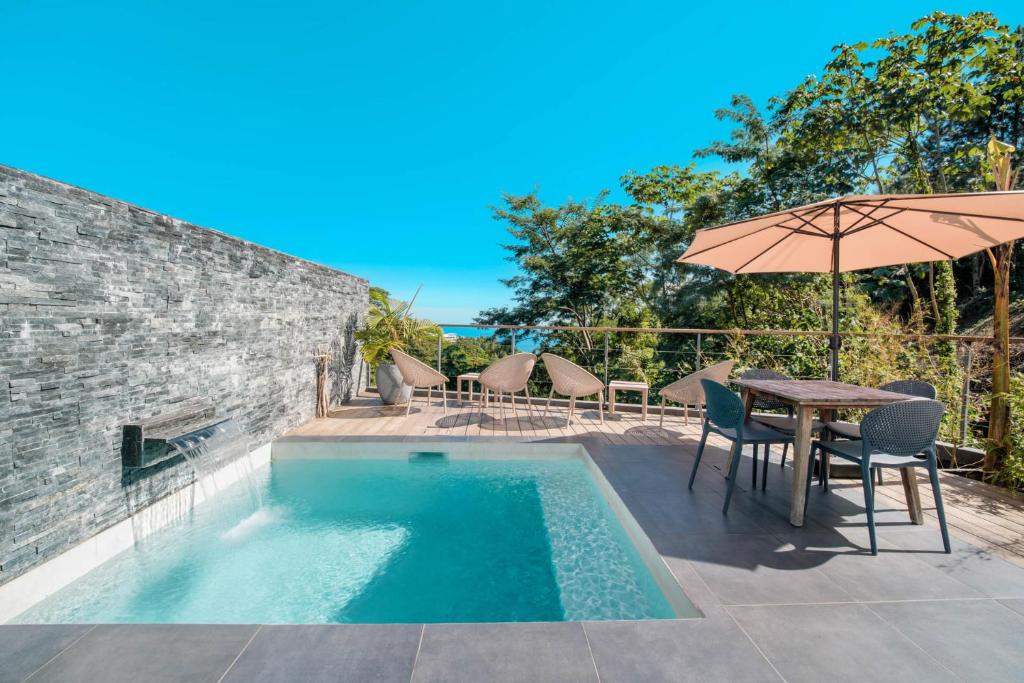 a swimming pool with a table and an umbrella at Peperu Lodge - bungalow piscine privée in Punaauia