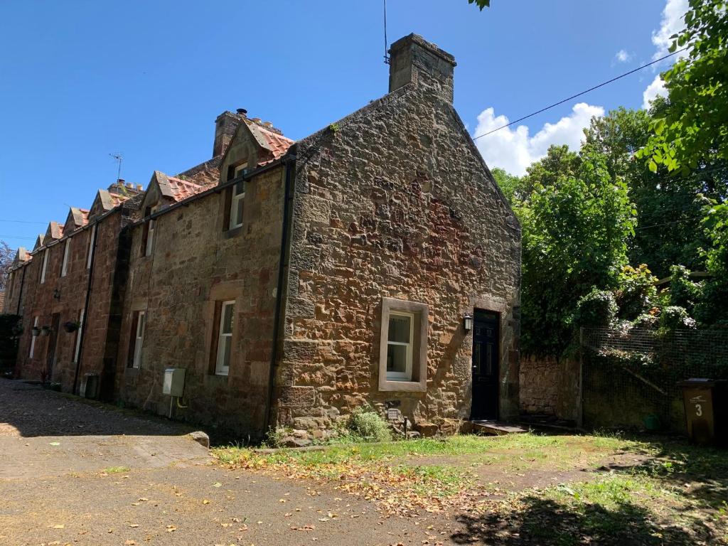 an old brick building sitting on the side of a road at Greenkeepers Rest in Longniddry
