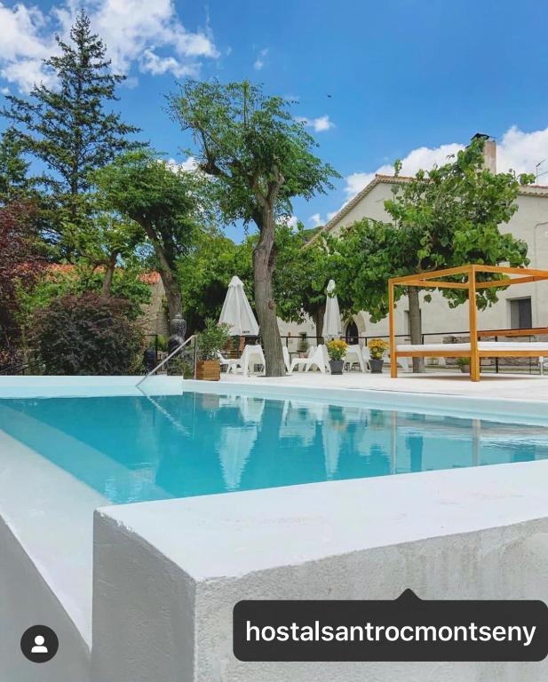 a swimming pool at a resort with a tree and chairs at Hostal Sant Roc in Montseny