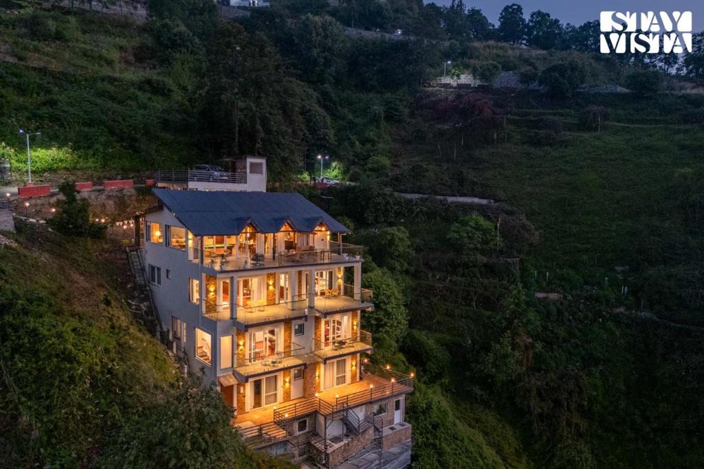 a large house on a hill with its lights on at StayVista at The Cloudberry Crest with BBQ & Bonfire in Rāmgarh