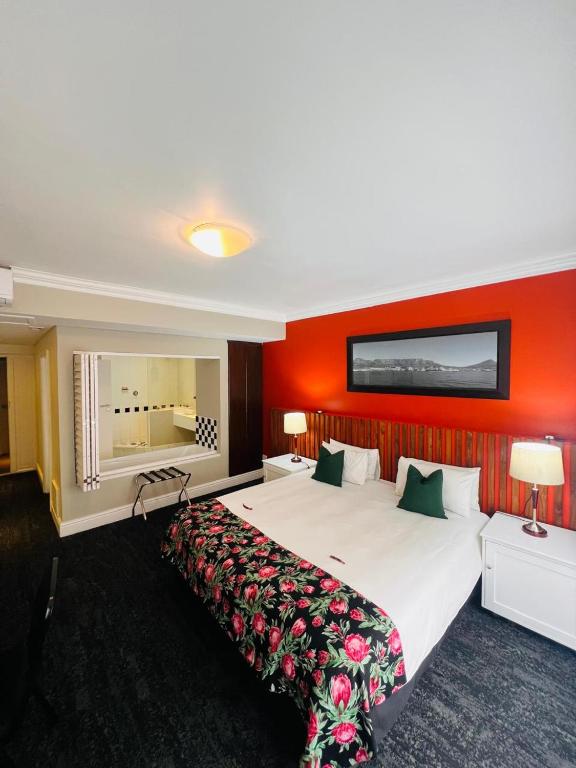 a hotel room with a large bed with red walls at Innscape Classic Hotel in Cape Town