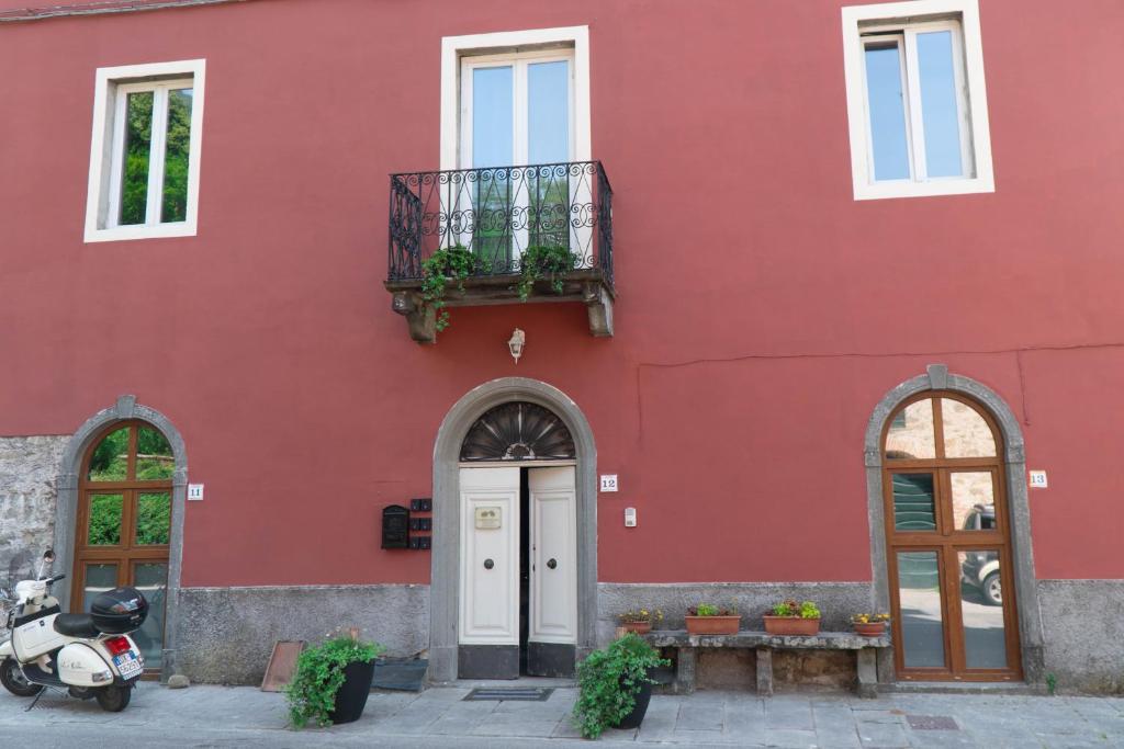 a red building with a scooter parked in front of it at Val di Lima House in Cocciglia