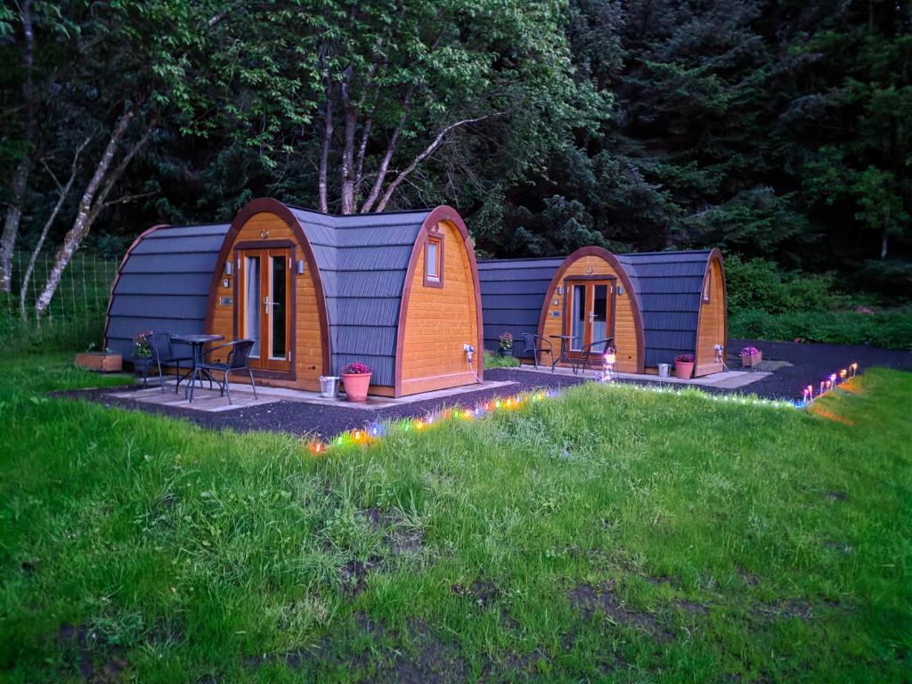 a small cabin in the grass with lights in the yard at Doune House Pods in Beauly