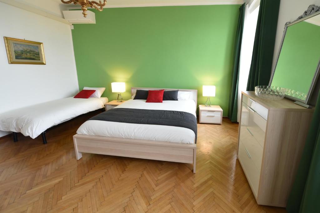 トリエステにあるB&B Al Giardino Leonorの緑の壁とウッドフロアの客室で、ベッド2台が備わります。
