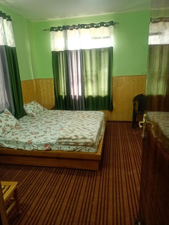 a bedroom with a bed with green walls and curtains at The Dupchen Cave View in Kaja