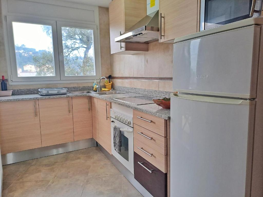 a kitchen with a white refrigerator and wooden cabinets at Villa Eucaliptus Lloret de Mar in Vidreres