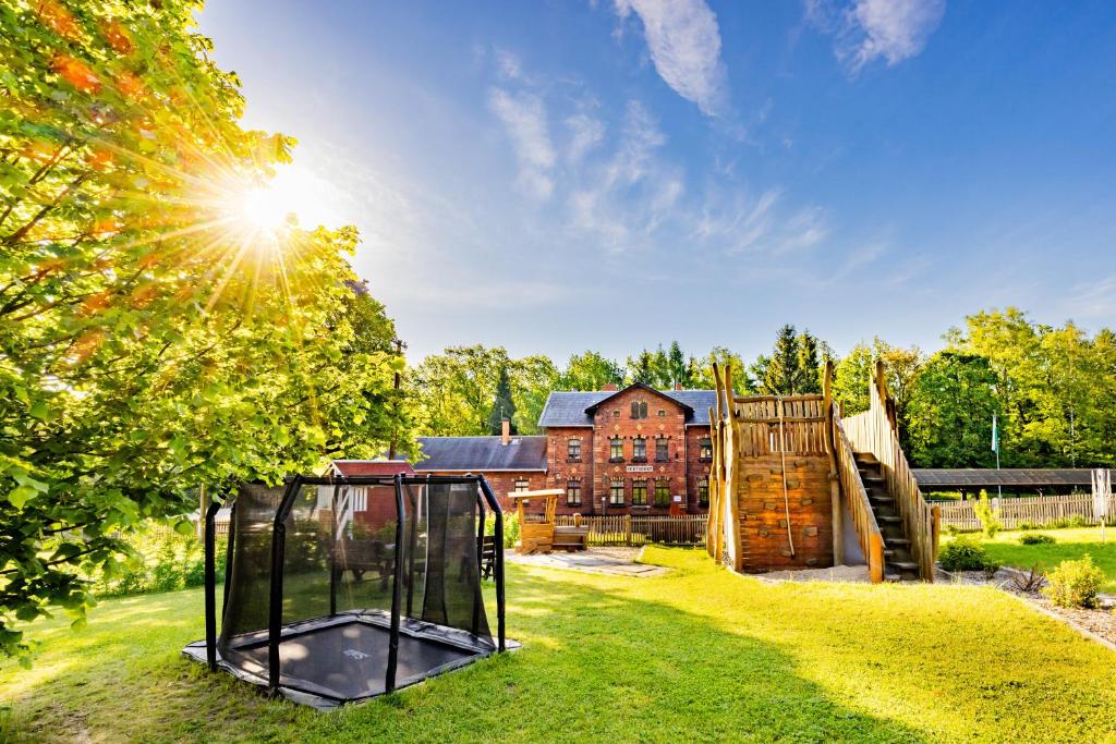 a playground in a yard with a house in the background at Ferienhaus Bimmelbahn 2 - Familienferienhaus 100 m am Dampflokbahnhof Sauna Trampolin Spielezimmer in Olbersdorf