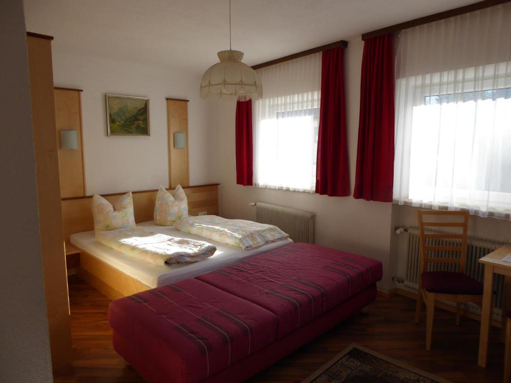 - une chambre avec un lit et une couverture rouge dans l'établissement Gasthaus Sonne, à Wenns